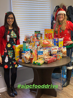 Dr. Gill and staff posing next to the food collected during the food drive