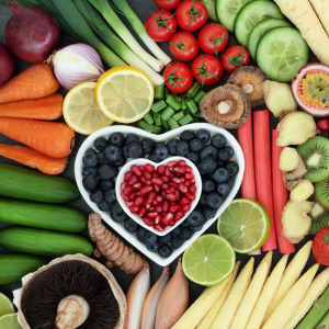 Color vegetables and fruit with some fruit in a heart-shaped bowl. 