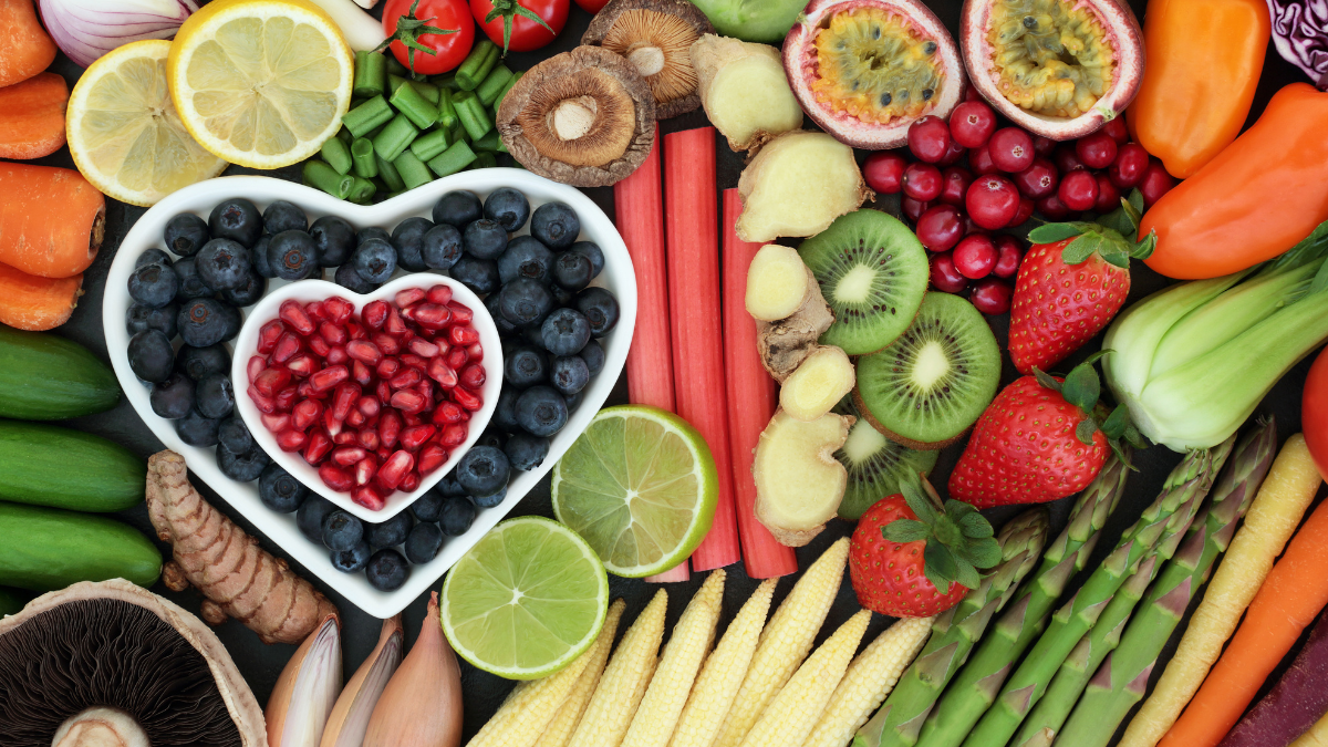 Color vegetables and fruit with some fruit in a heart-shaped bowl. 