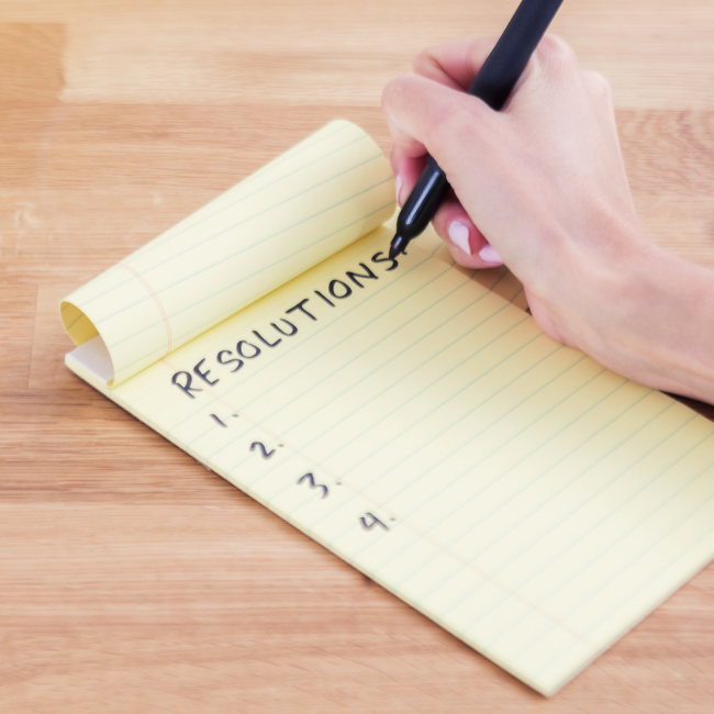 Person writing resolutions in a notebook