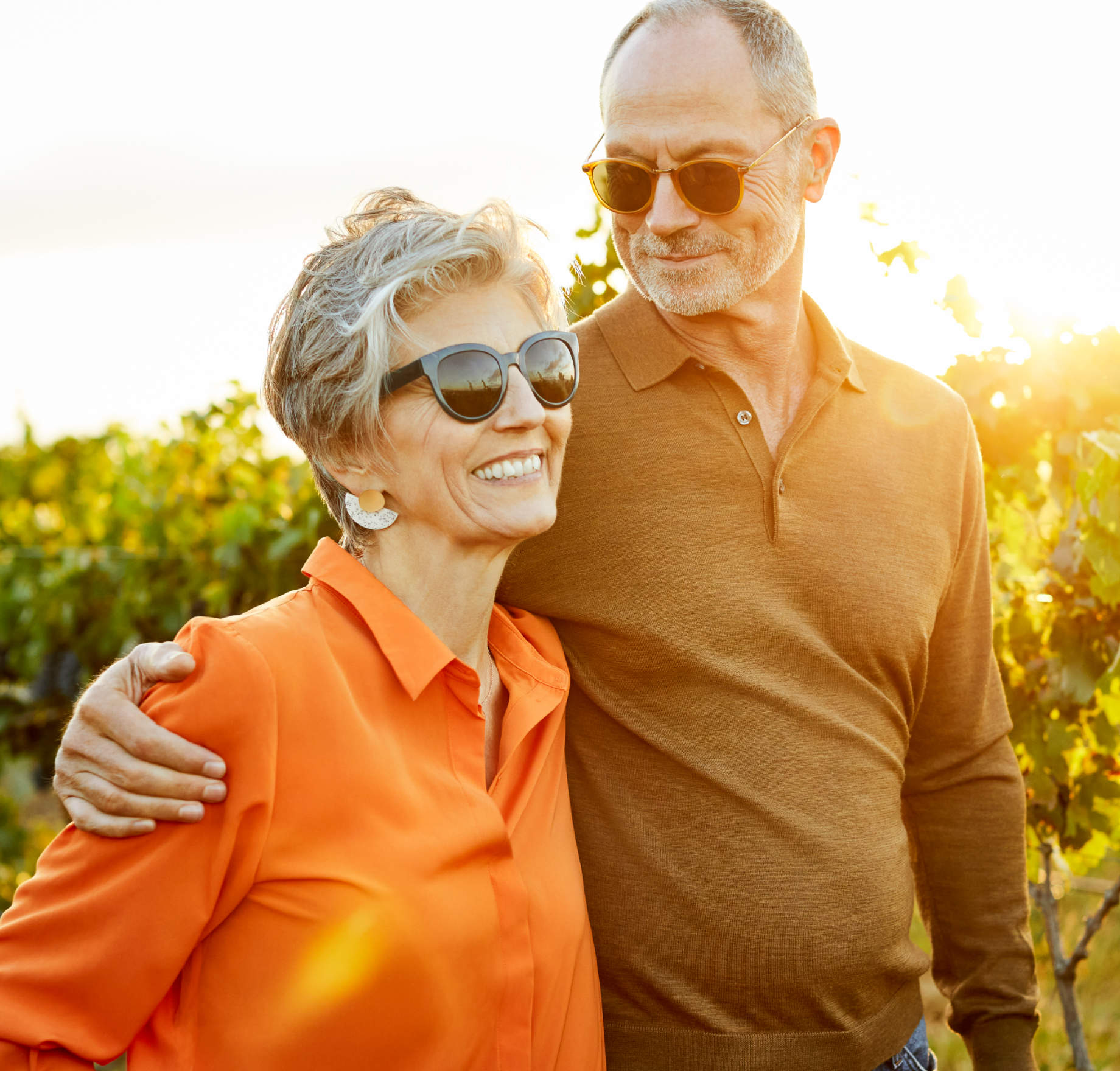 Older couple smiling outdoors at sunset.