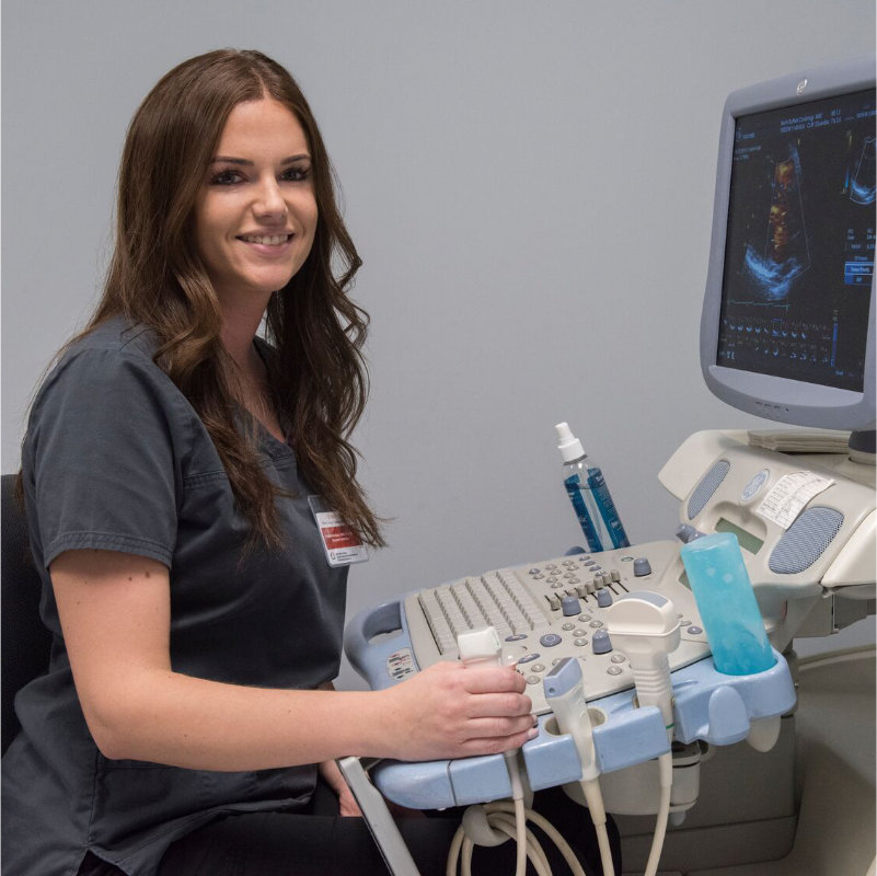 A smiling medical professional operating an ultrasound machine.