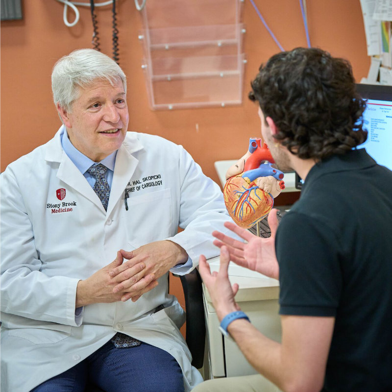 A cardiologist at Stony Brook Medicine discusses heart health with a patient, using a heart model for explanation.
