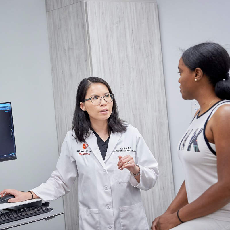 Doctor Xun Lian consulting with a patient in an examination room.