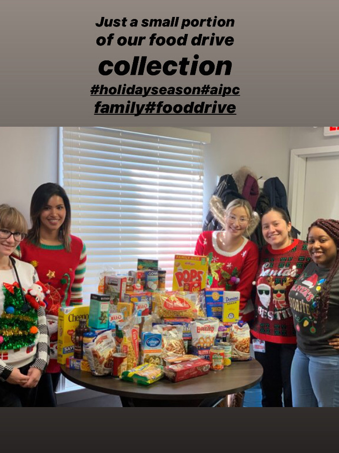 Dr. Gill and staff posing next to the food collected during the food drive
