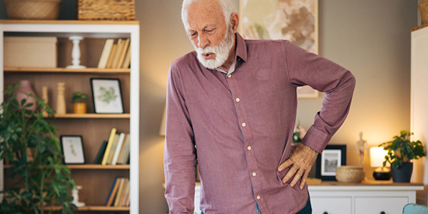 male patient expressing pain while holding hip