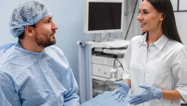 Male in medical gown speaking with medical professional
