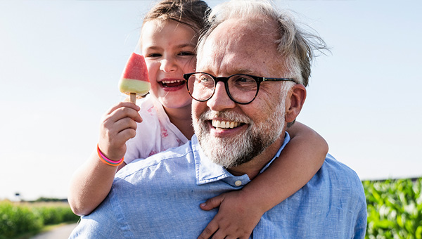 Child with ice pop hugging father