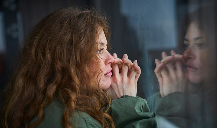 Woman looking out of window into her reflection